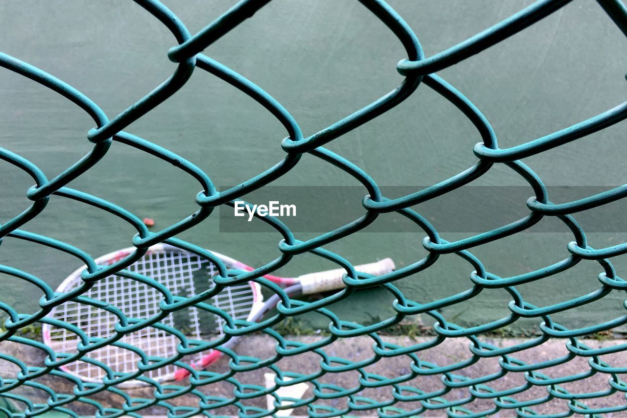 Badminton racket on road seen through chainlink fence