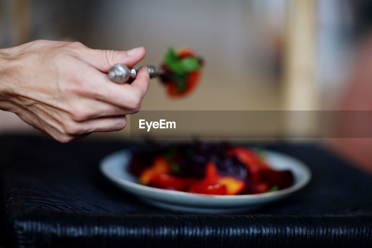 Cropped hand holding food in spoon