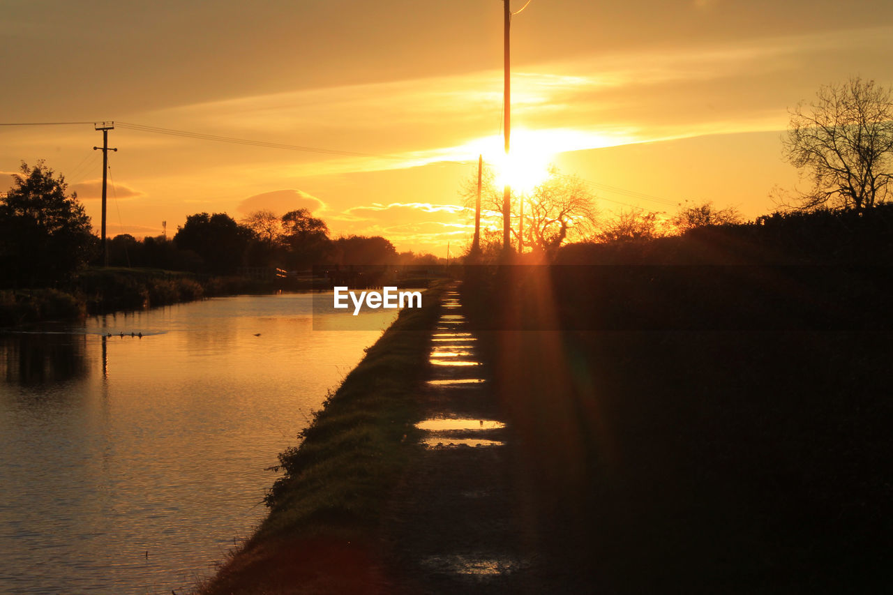 Scenic view of river against orange sky at sunset