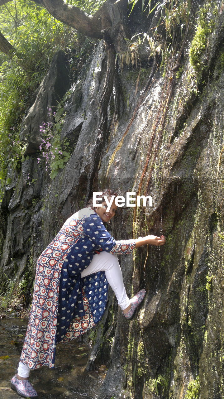 Woman leaning on rock in forest