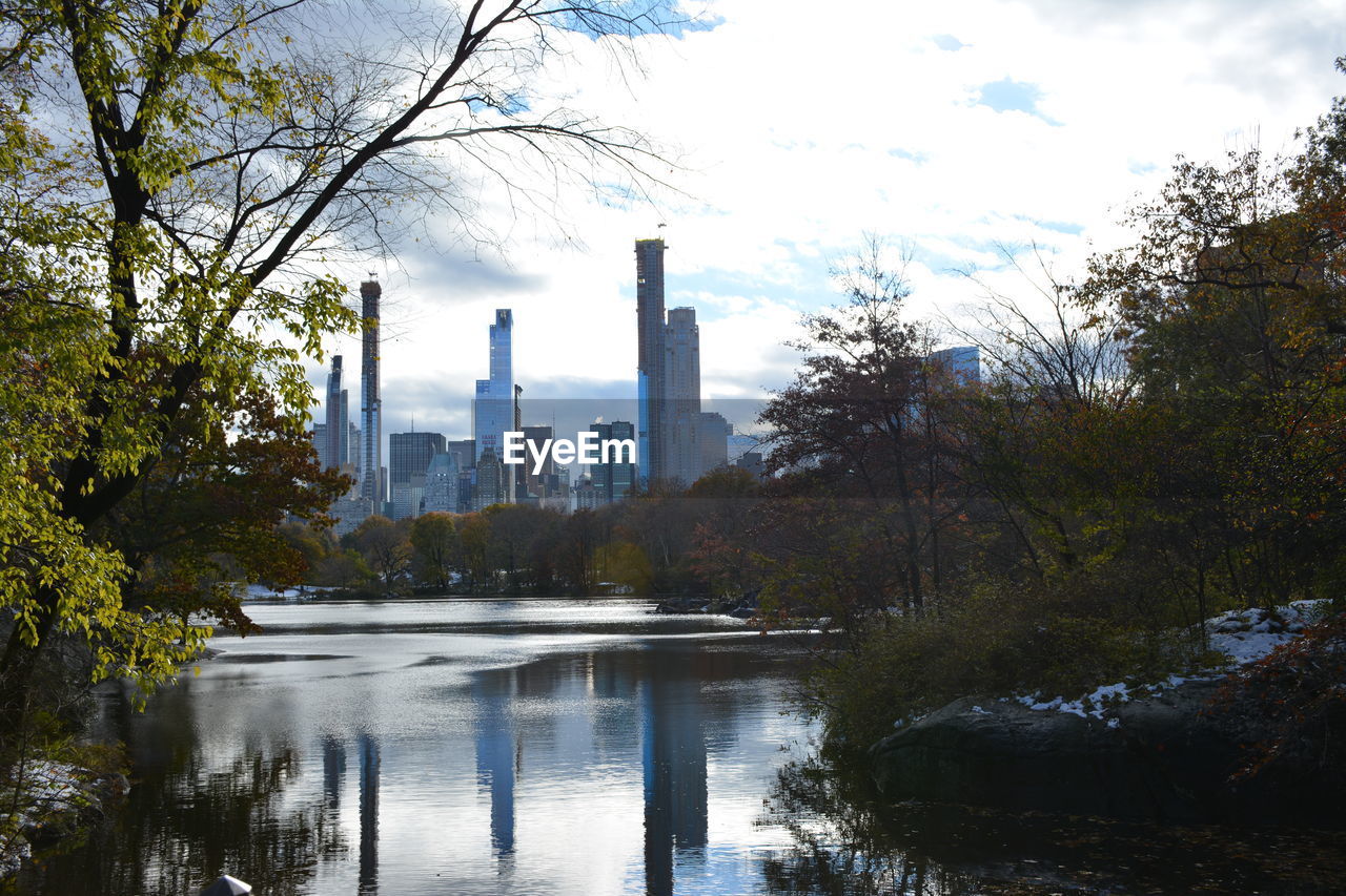 reflection, tree, water, architecture, built structure, plant, building exterior, river, sky, nature, park, city, autumn, cloud, skyscraper, office building exterior, building, no people, waterway, landscape, outdoors, body of water, travel destinations, industry, morning, environment, day, pond, tower, business finance and industry, urban skyline
