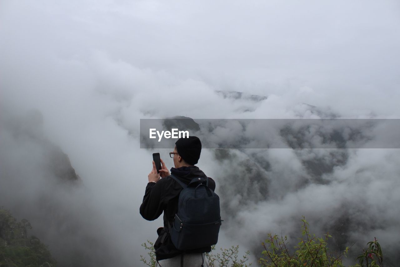 Rear view of man photographing in foggy weather