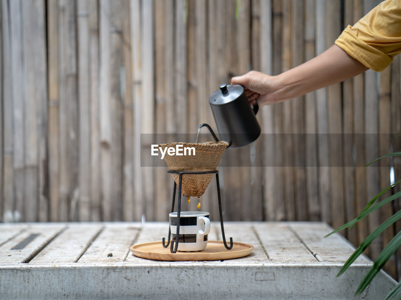 Cropped hand of woman pouring water in coffee cup