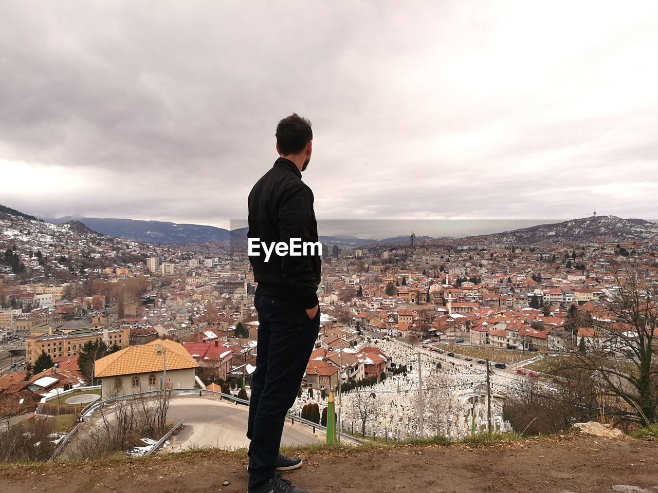 Rear view of man looking at cityscape against sky