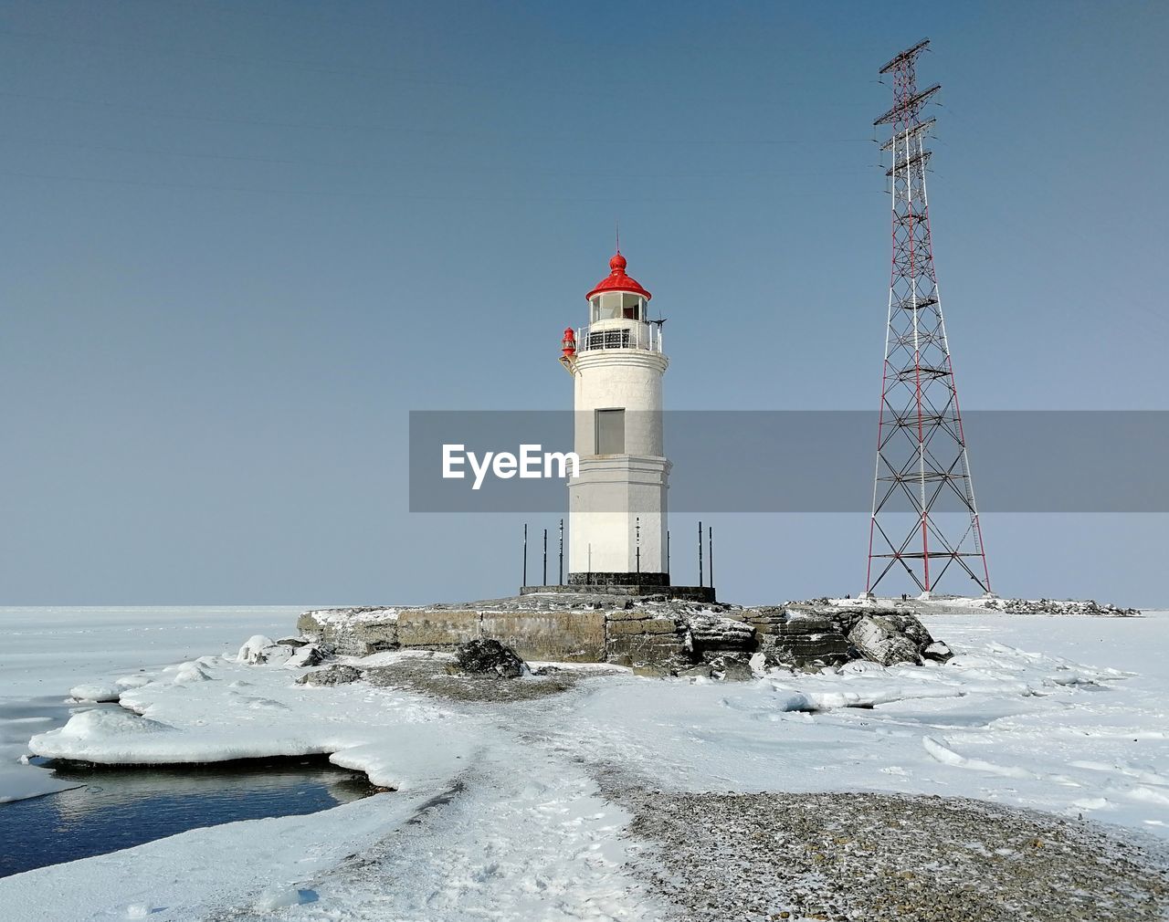 Lighthouse by sea against clear sky