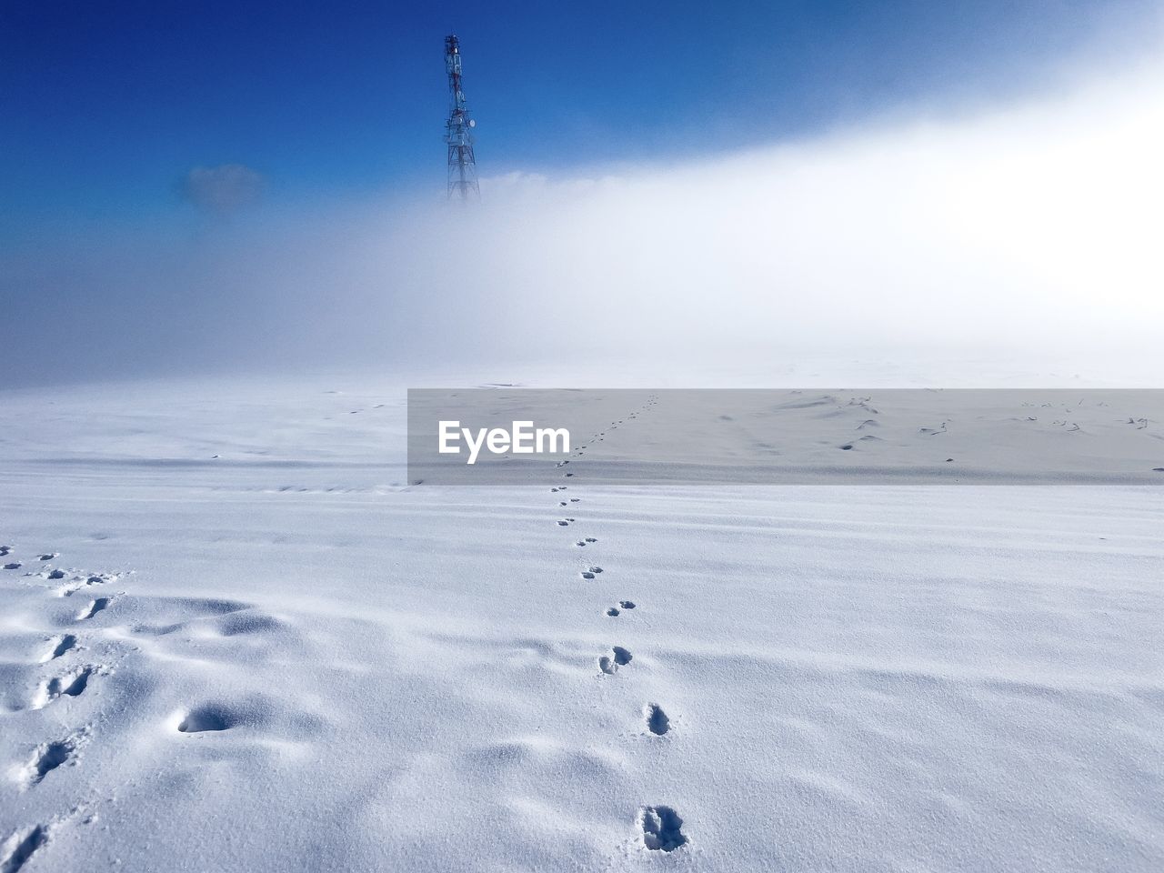 Footprints in the snow leading to a tower in the distance