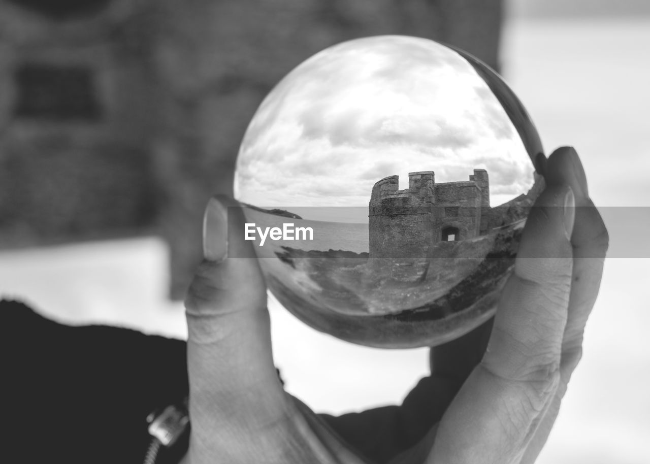 Close-up of hand holding crystal ball with reflection