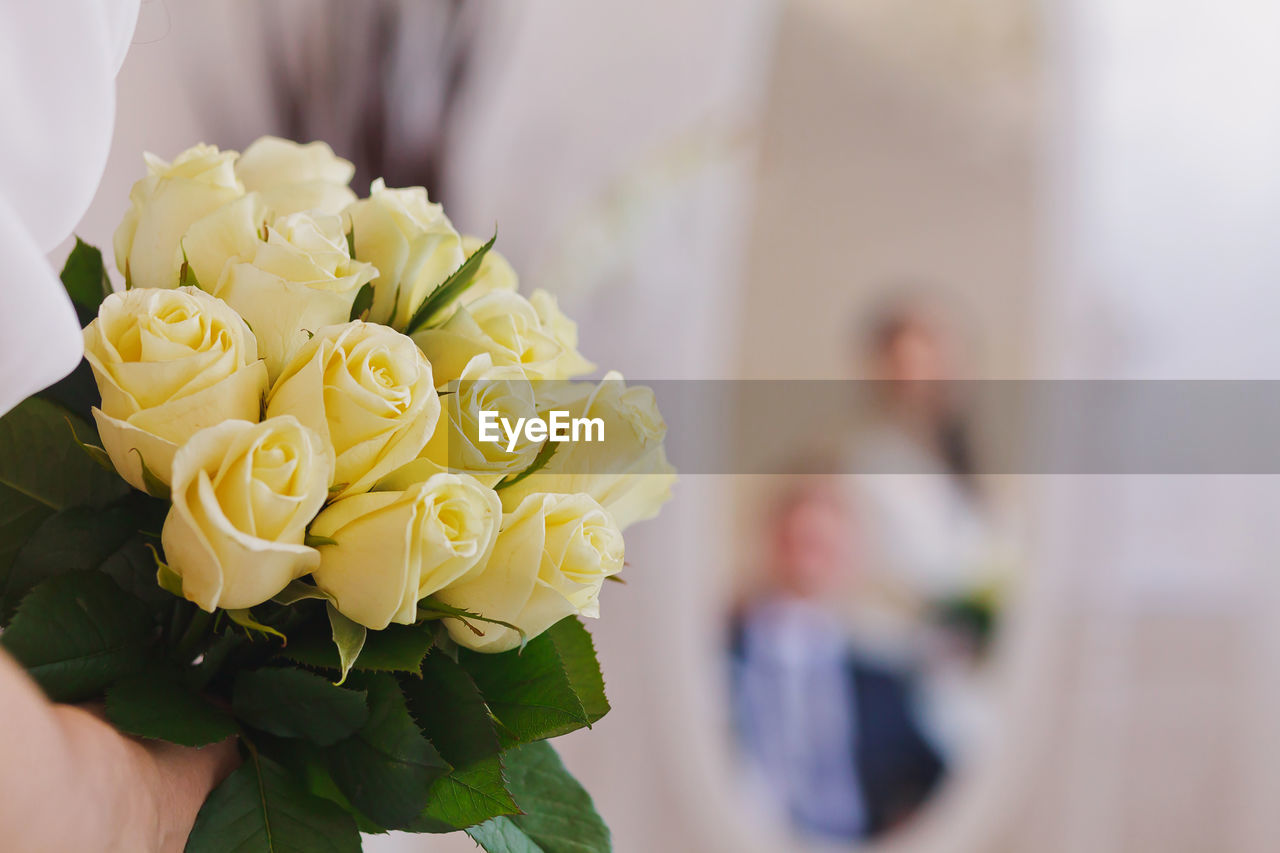 Cropped image of hand holding roses during wedding