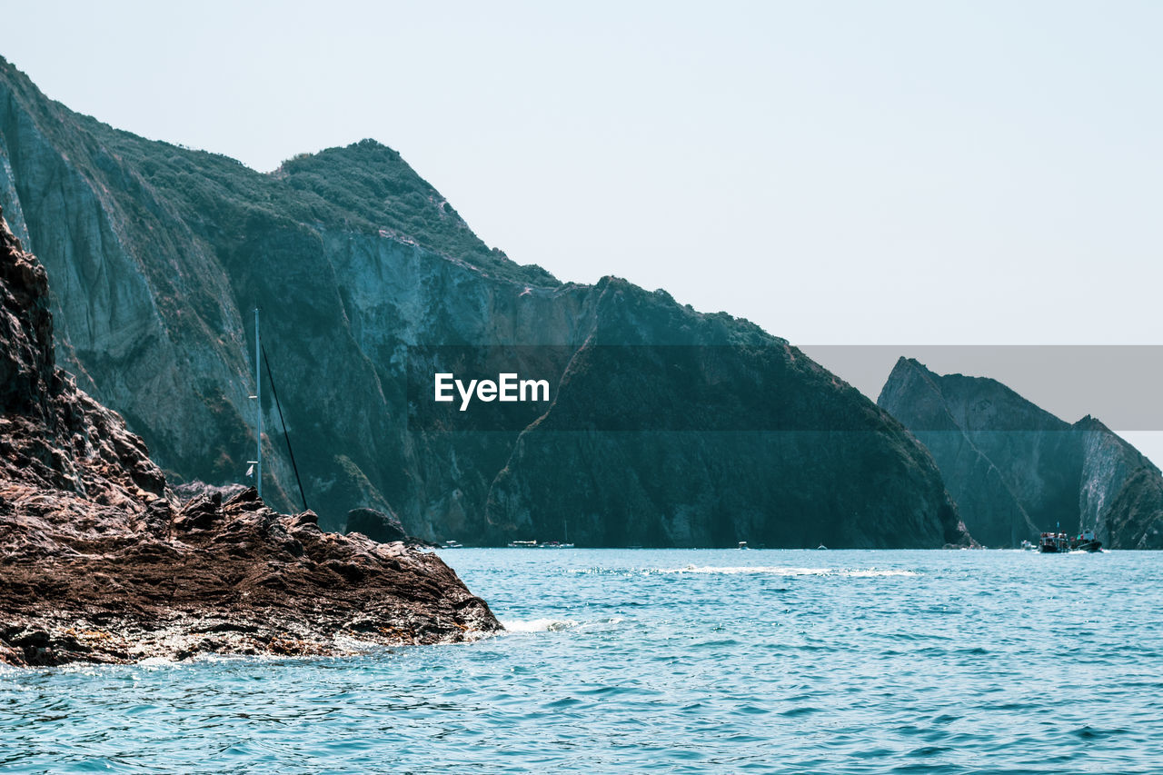 SCENIC VIEW OF SEA AND MOUNTAIN AGAINST CLEAR SKY