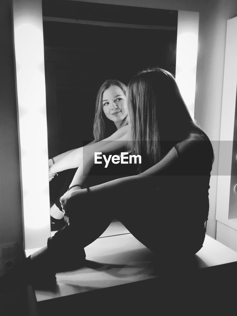 Woman sitting on table reflecting in mirror