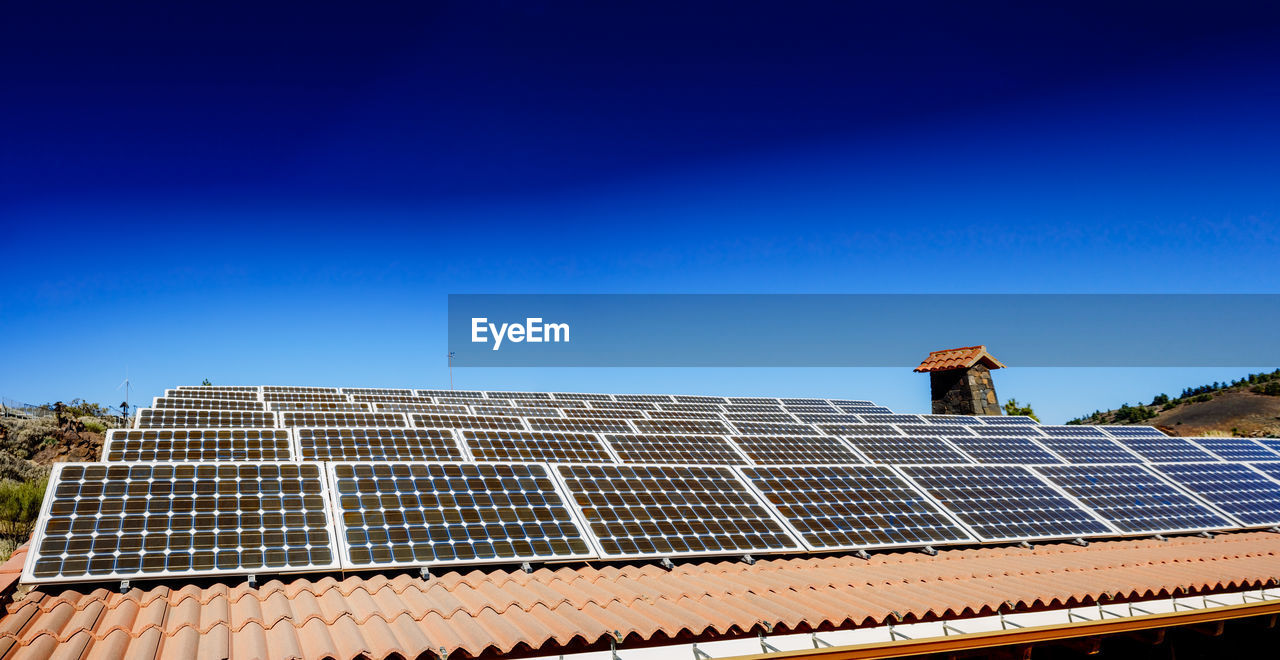 Small solar panels on the roof of a house in the sunny mountain.