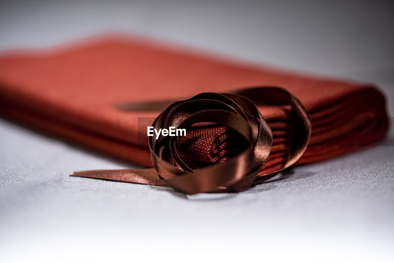 CLOSE-UP OF RED ROSE ON BOOK