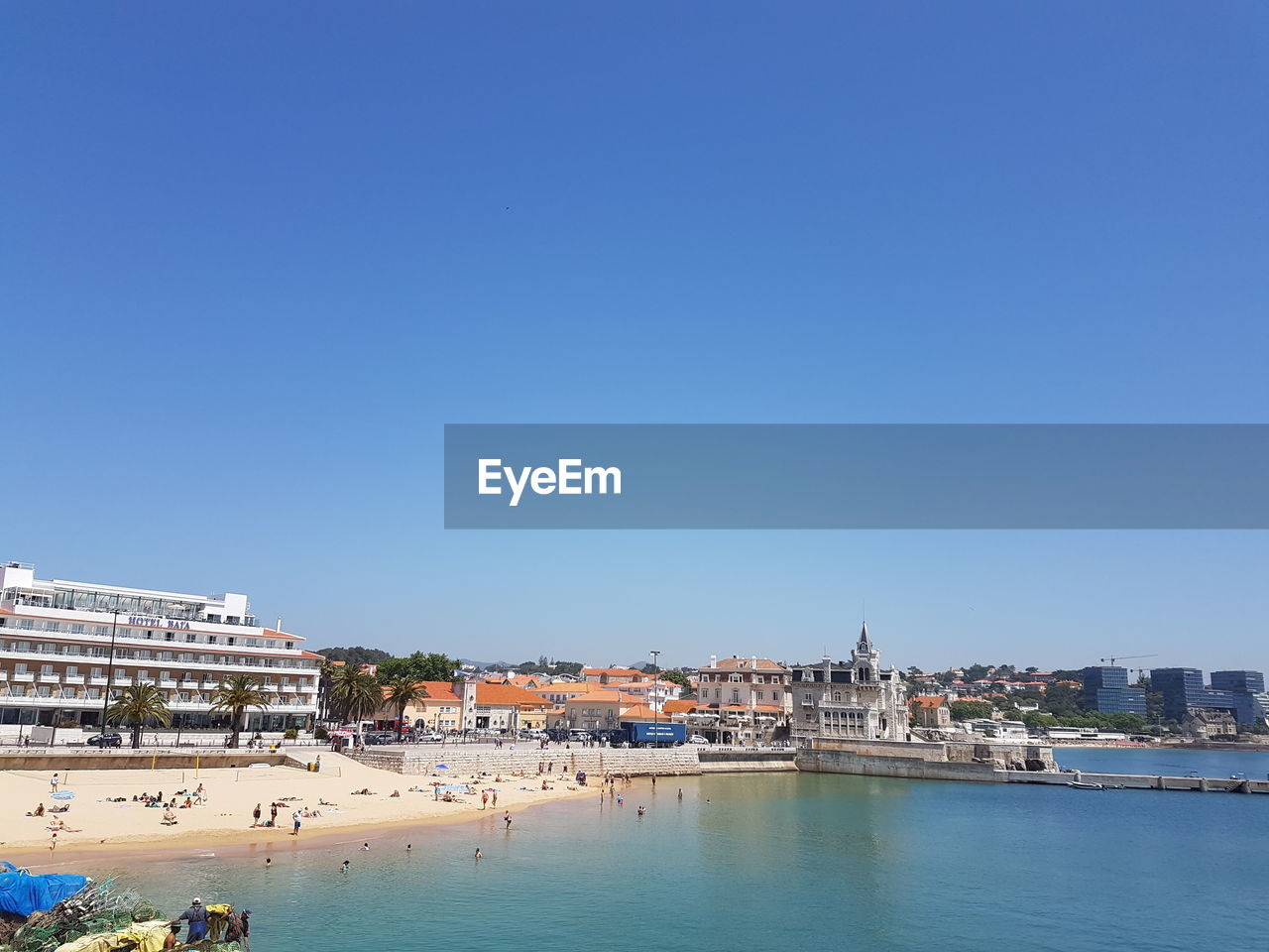 View of buildings by river against blue sky