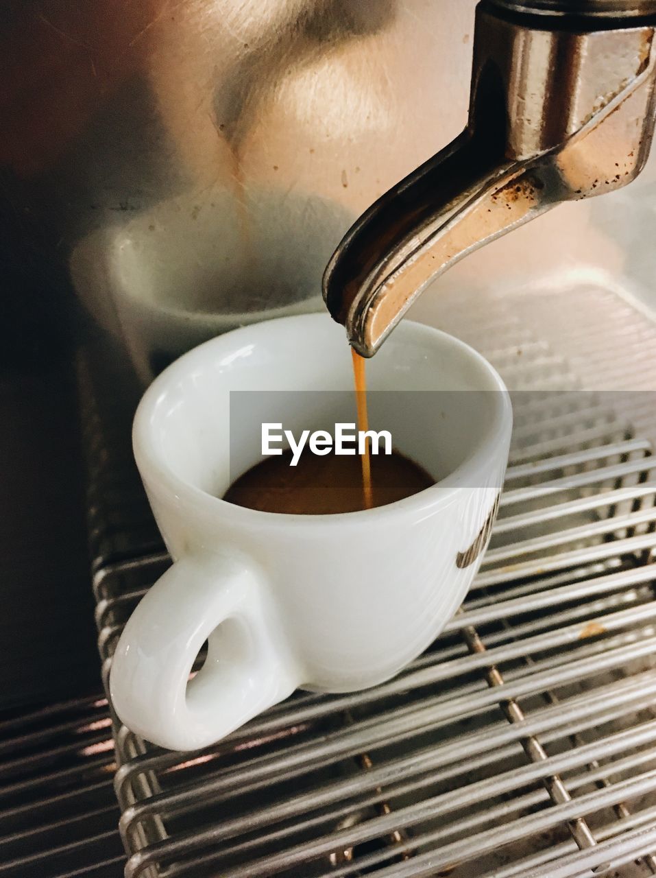 Close-up of coffee dripping down into espresso cup