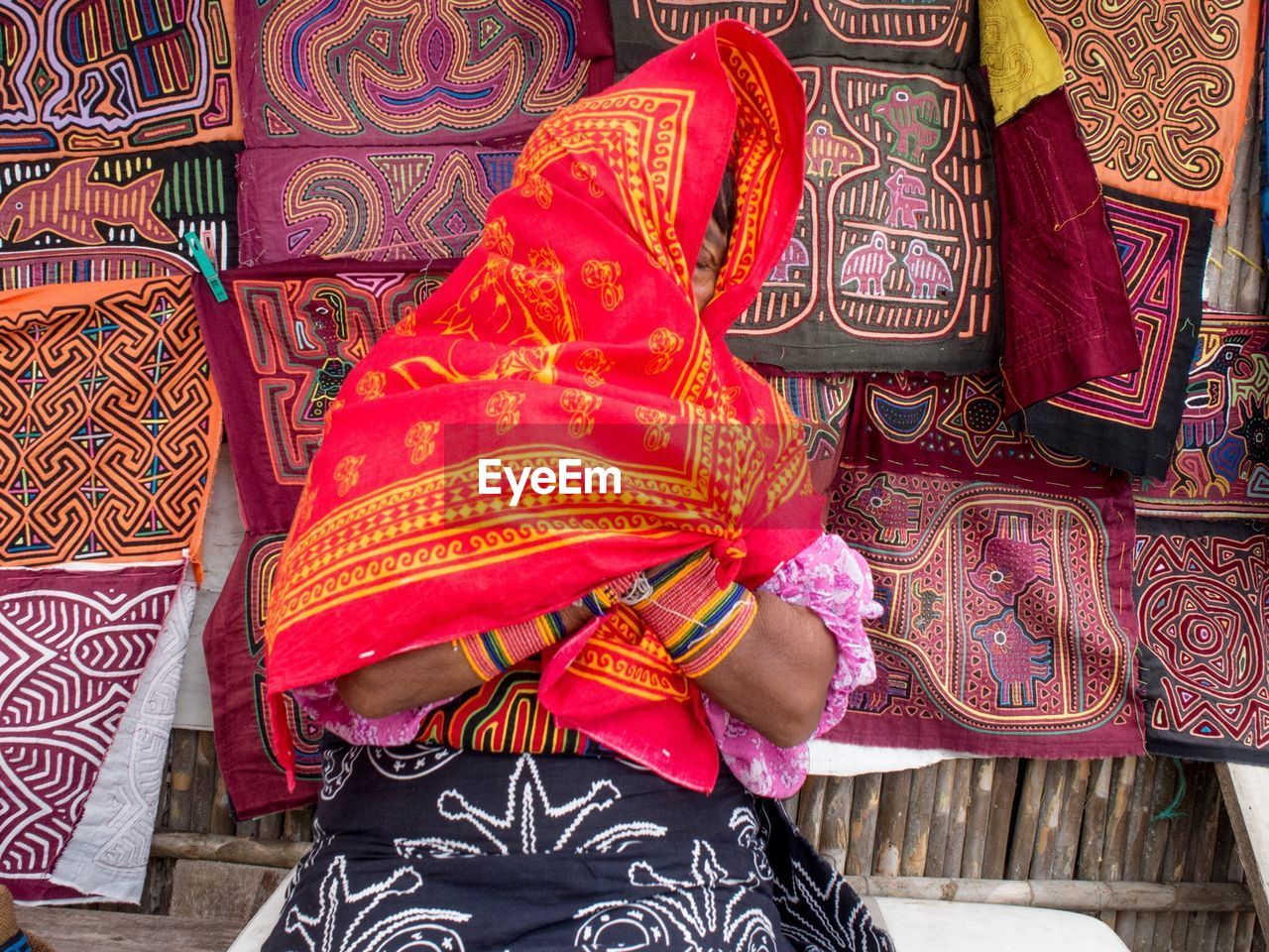 Woman covering face with red towel in market