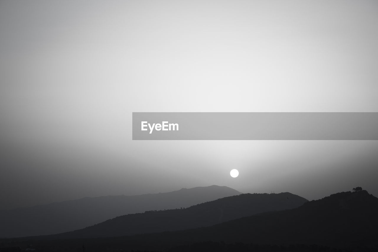 mountain, sky, scenics - nature, horizon, beauty in nature, tranquility, moon, silhouette, tranquil scene, nature, environment, no people, dawn, fog, copy space, astronomical object, landscape, mountain range, moonlight, morning, darkness, cloud, outdoors, full moon, night, haze, non-urban scene, idyllic, light, mist