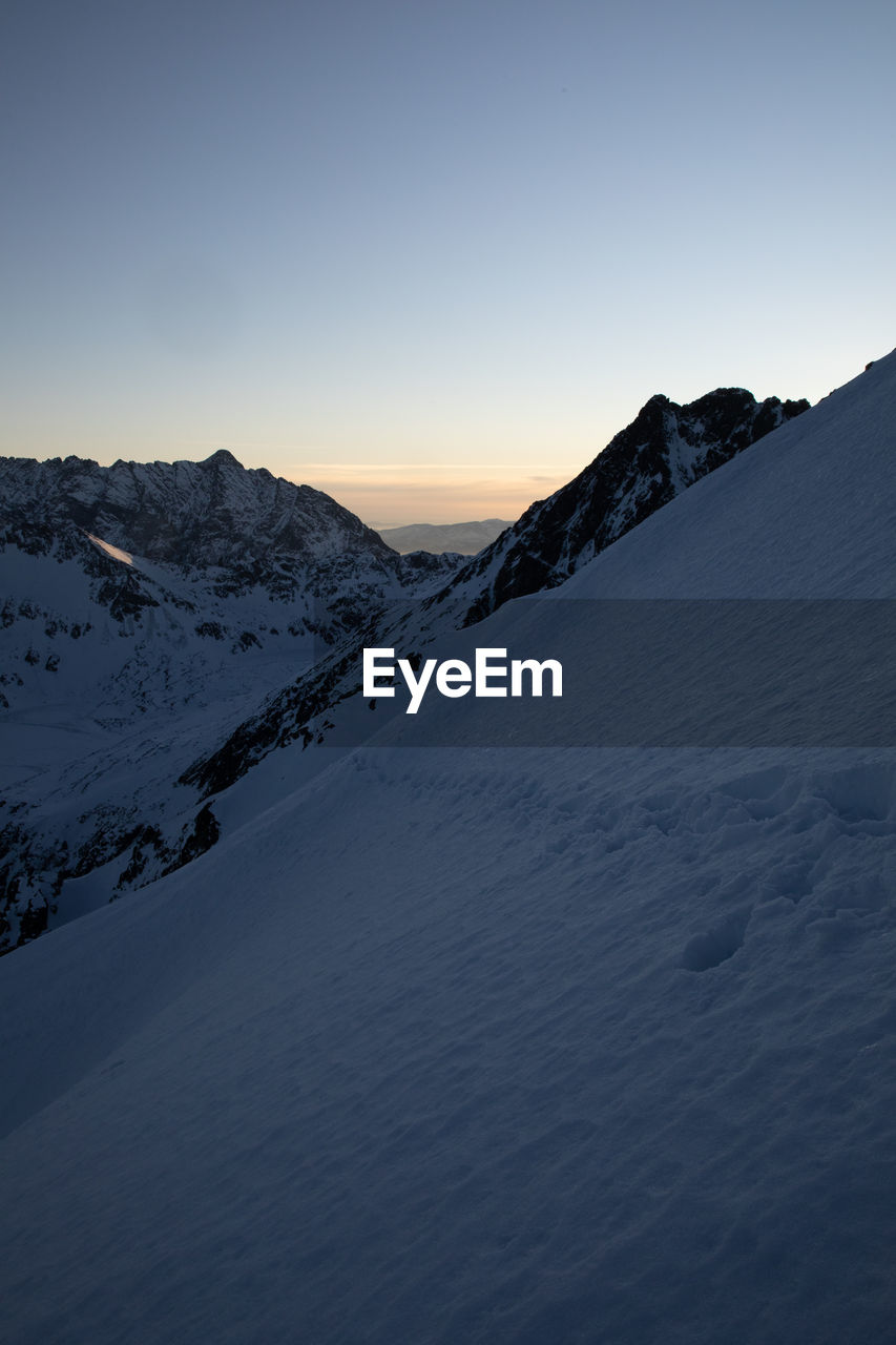 Scenic view of snow covered mountains against sky during sunset