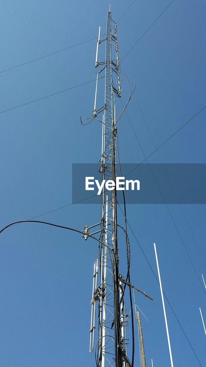 LOW ANGLE VIEW OF ELECTRICITY PYLONS AGAINST CLEAR BLUE SKY