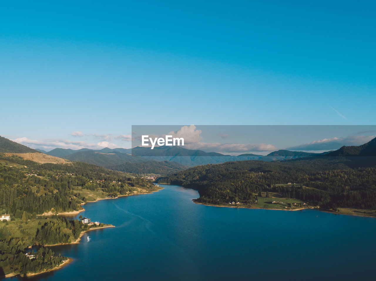 Scenic view of lake and mountains against blue sky