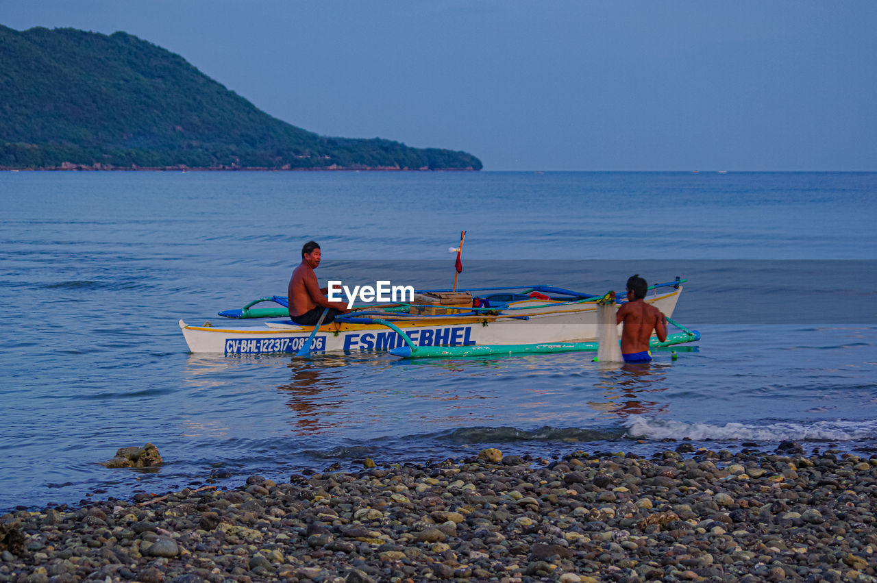 PEOPLE ON SHORE AGAINST SKY