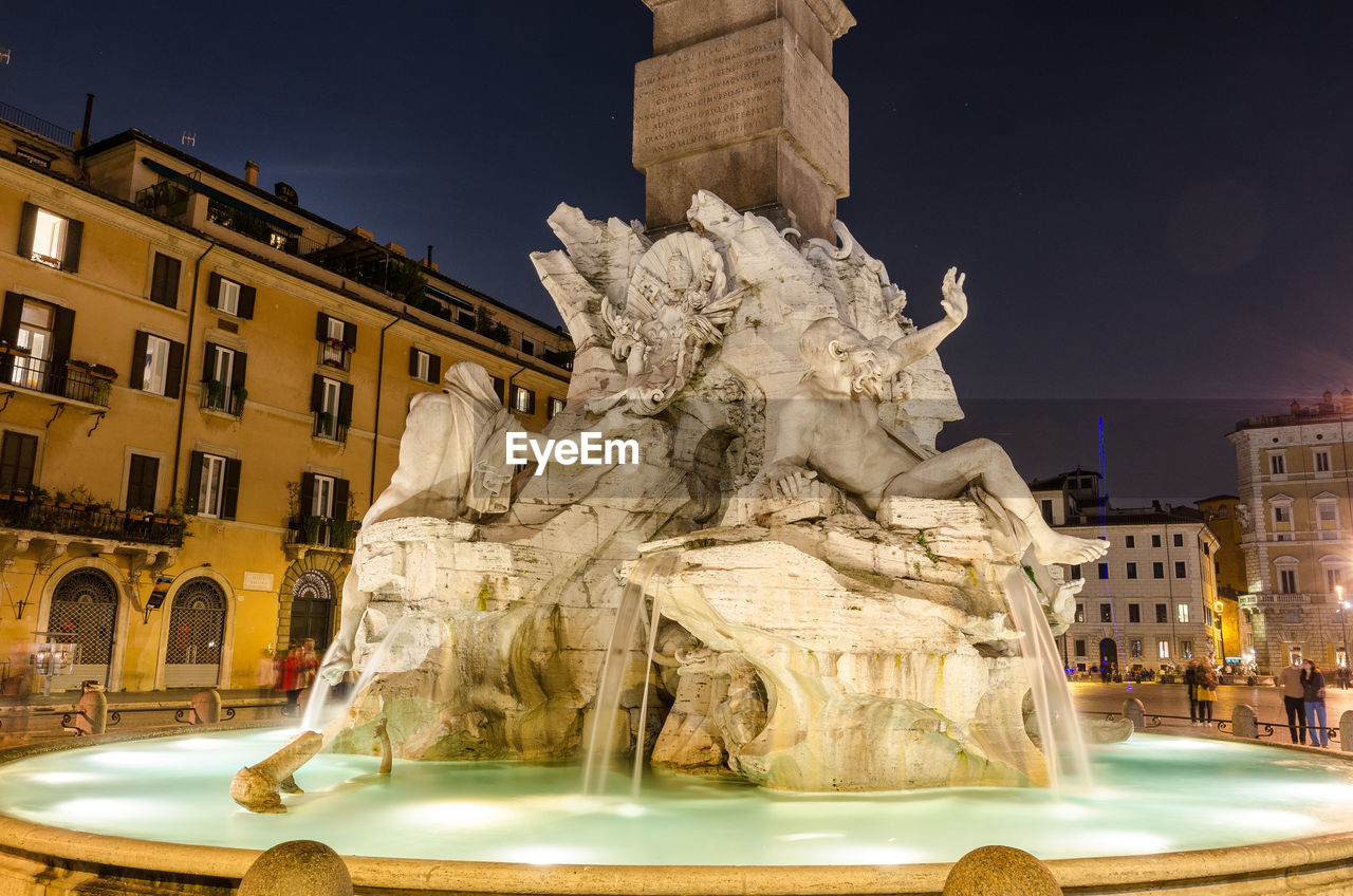 Statue at fountain in city against sky