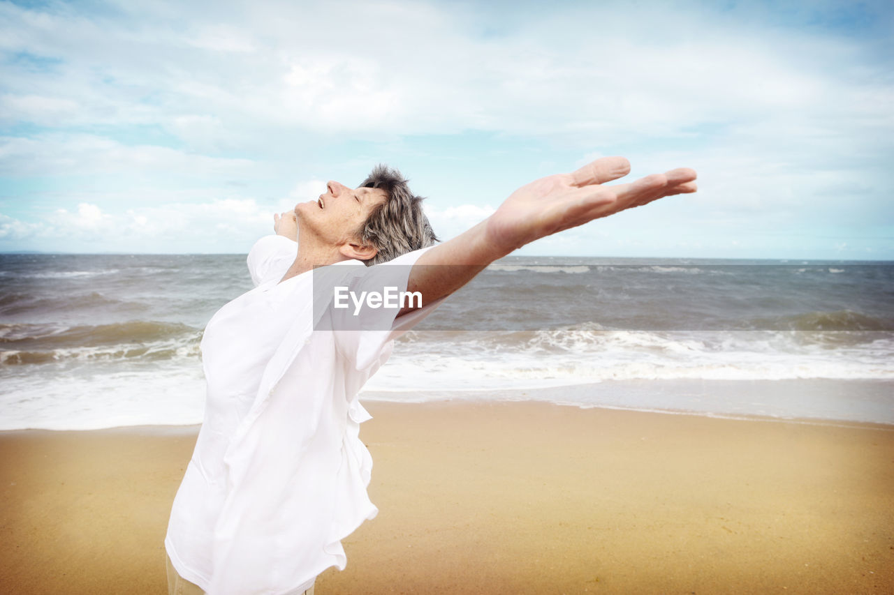 Side view of senior woman standing at beach