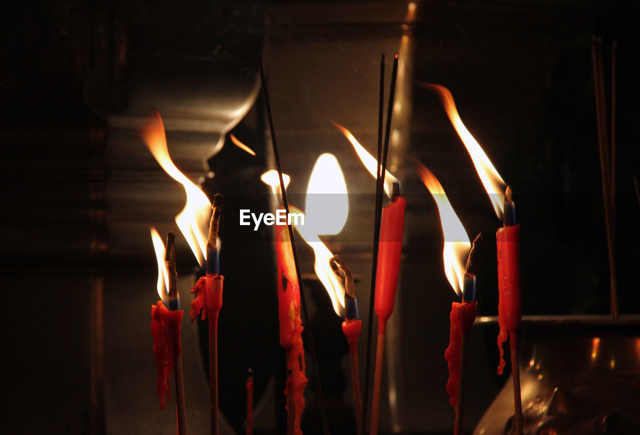 Close-up of lit candles in buddhist temple