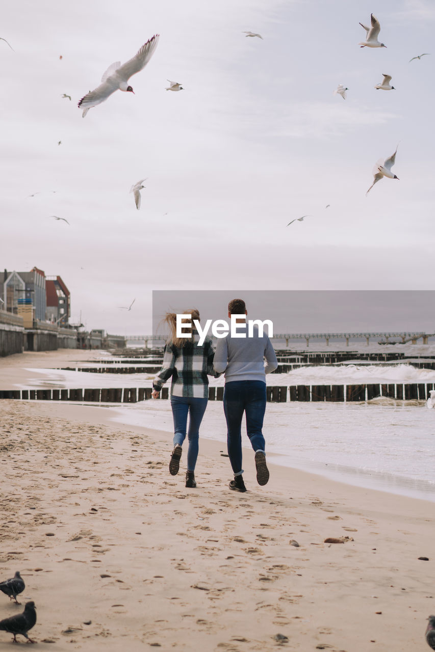 Close up of couple running near the sea and looking to each other.