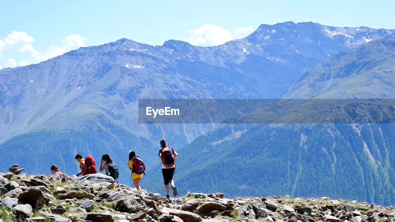 People hiking on mountain against sky