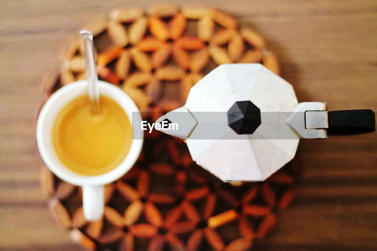 Directly above shot of cup and coffee maker on table