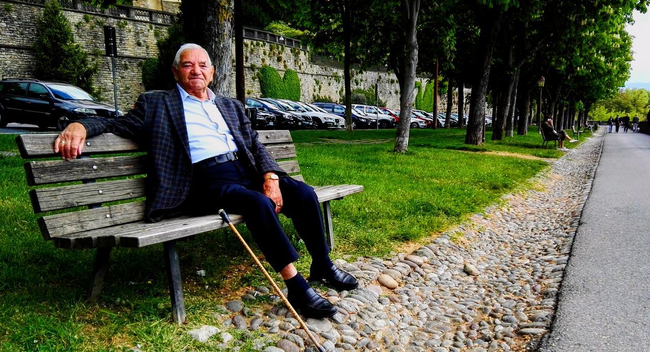 PORTRAIT OF MAN SITTING ON PARK