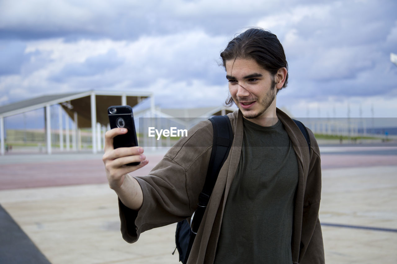 PORTRAIT OF MAN WITH CAMERA IN CITY