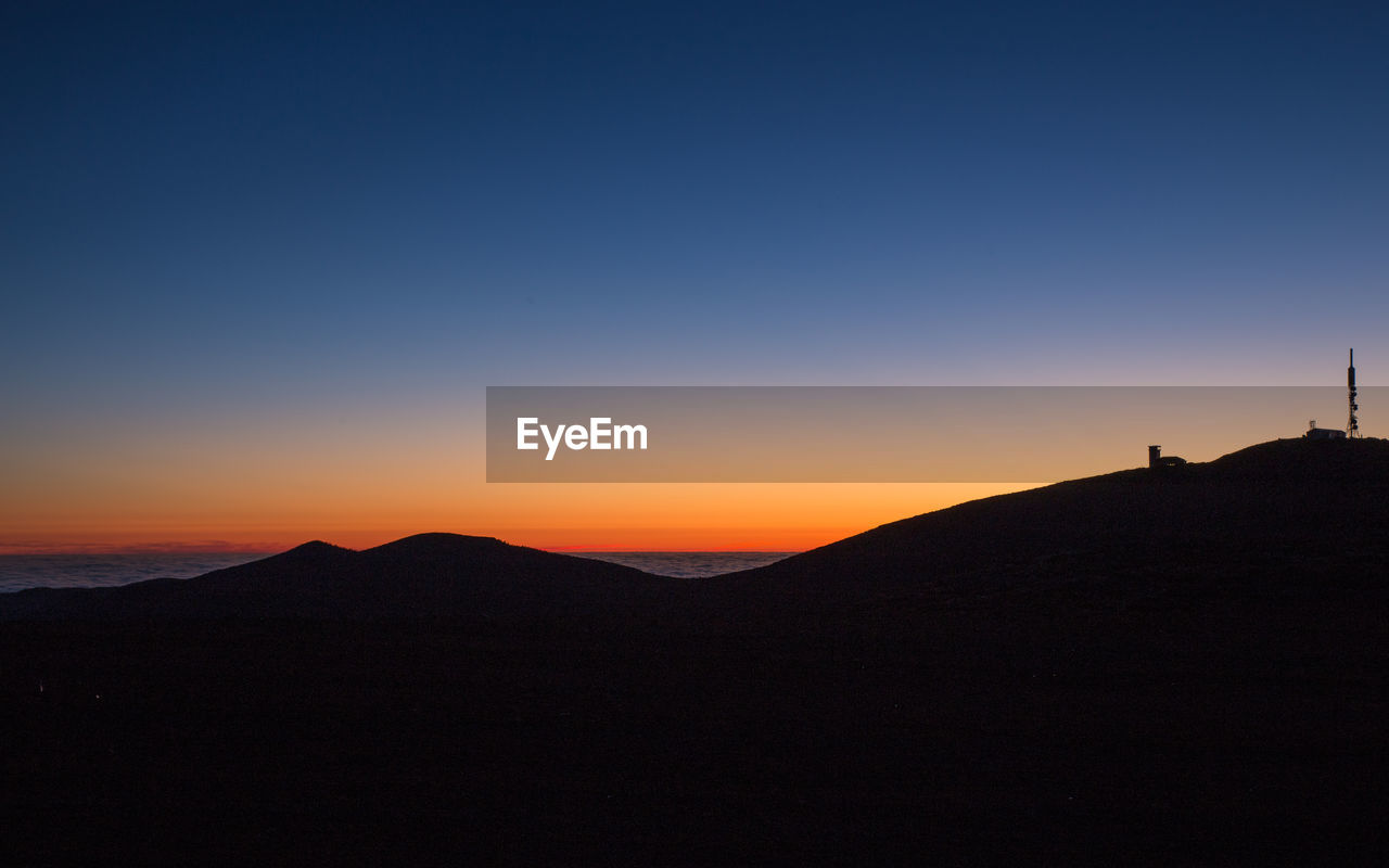 Scenic view of silhouette mountains against clear sky during sunset