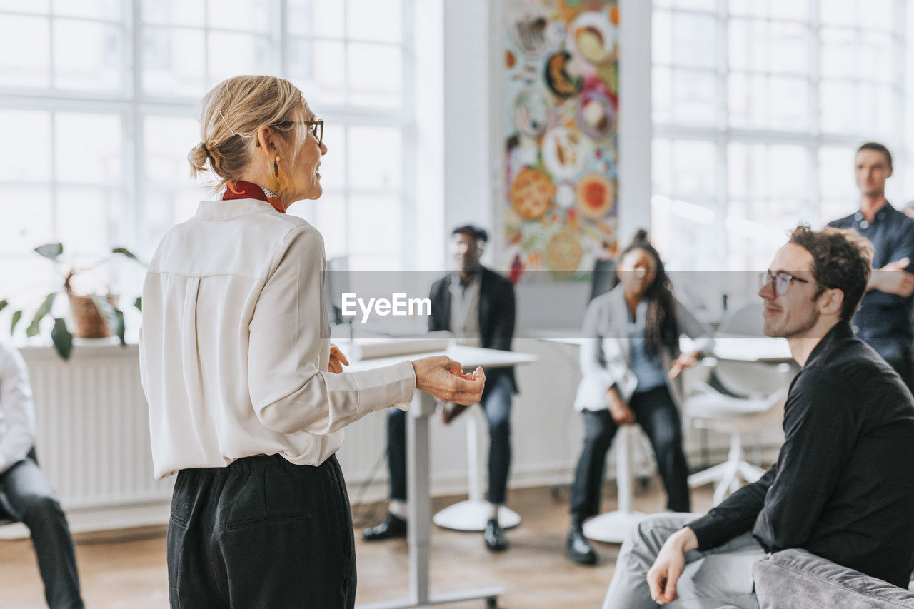 Mature businesswoman discussing with colleagues in meeting at office