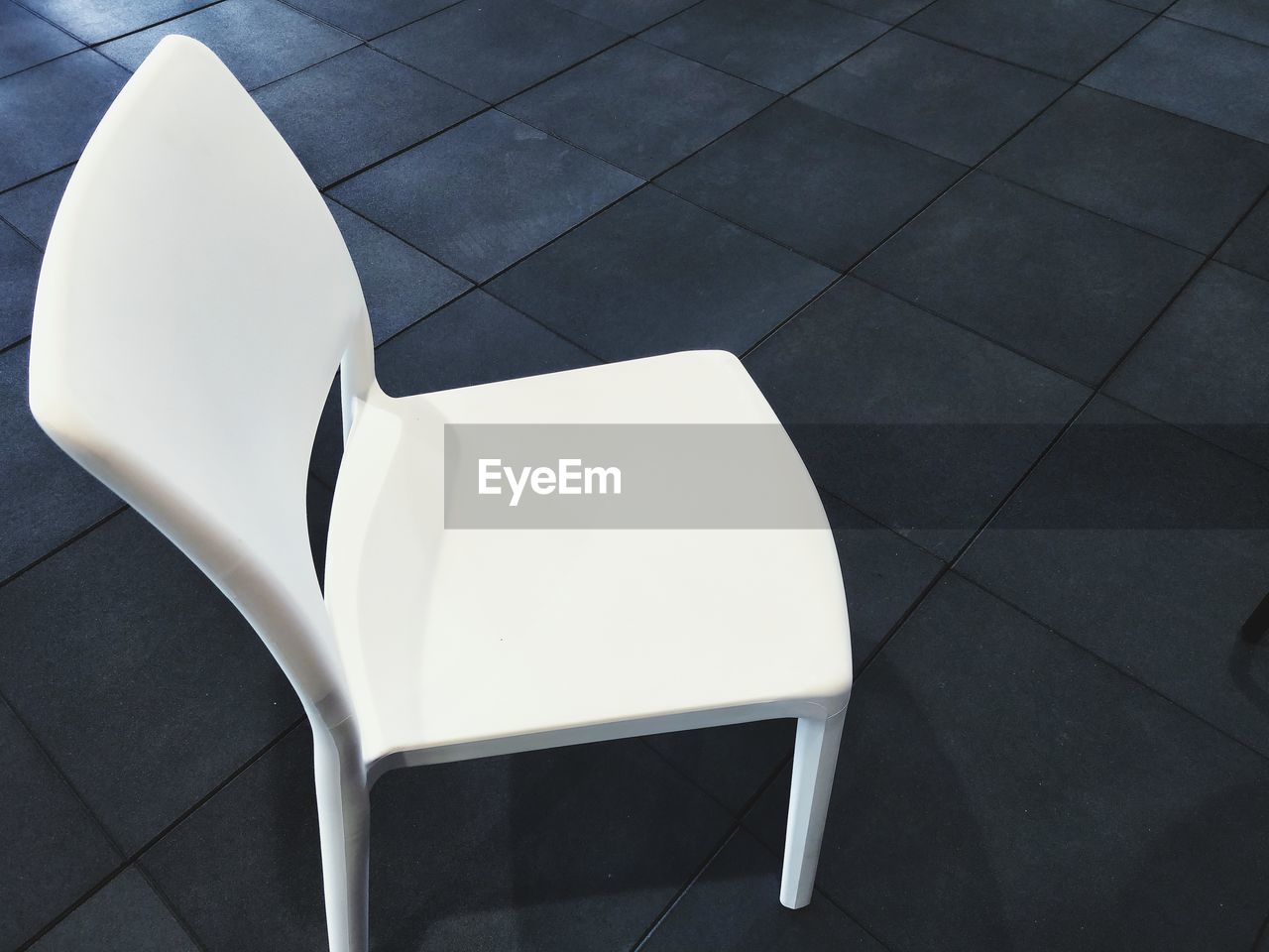 High angle view of empty white chair on tiled floor