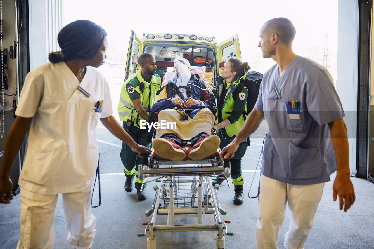 Healthcare workers pushing patient on gurney in hospital