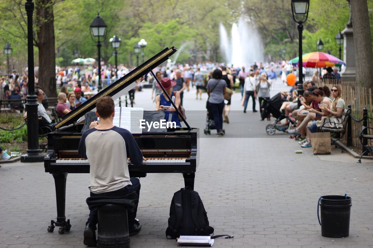 Rear view of man playing piano on street at park