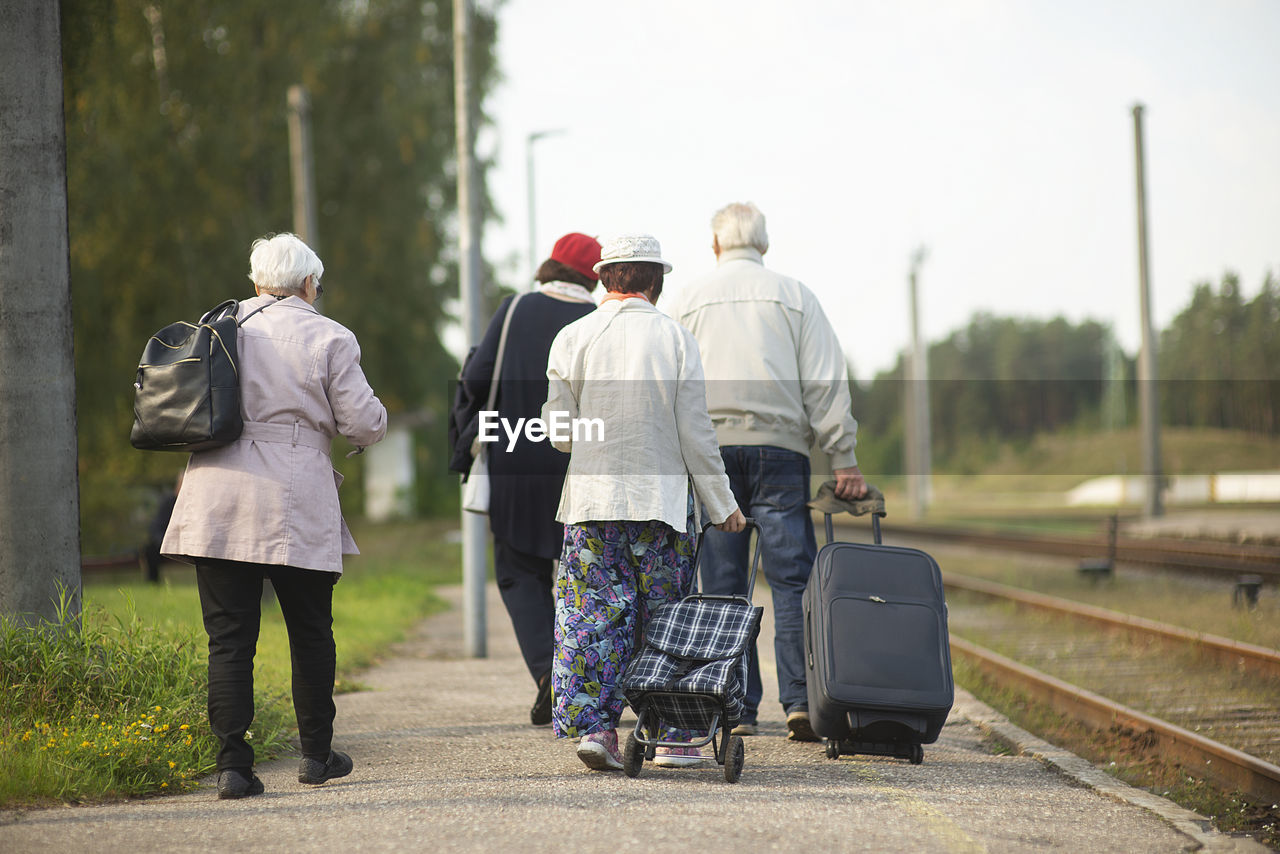 Rear view of a group of seniors elderly old people with luggage waiting for a train to travel