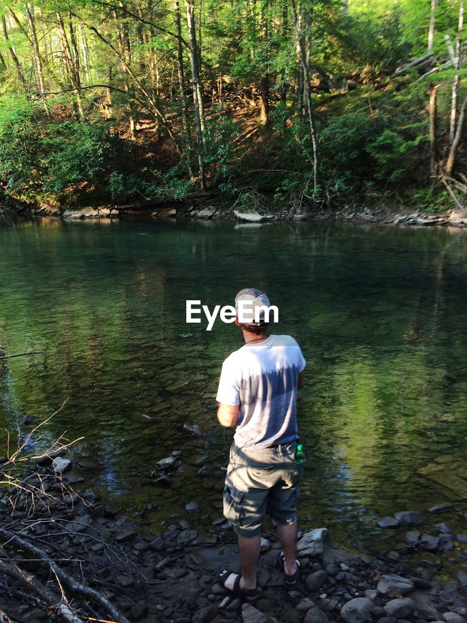 MAN STANDING ON RIVERBANK