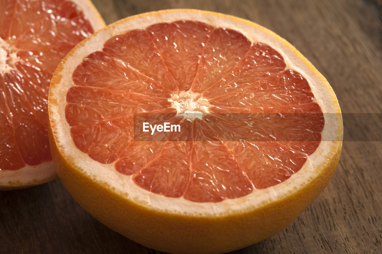 Fresh half pink or rose grapefruit in a close up view on a wooden table showing the juicy tangy pulp