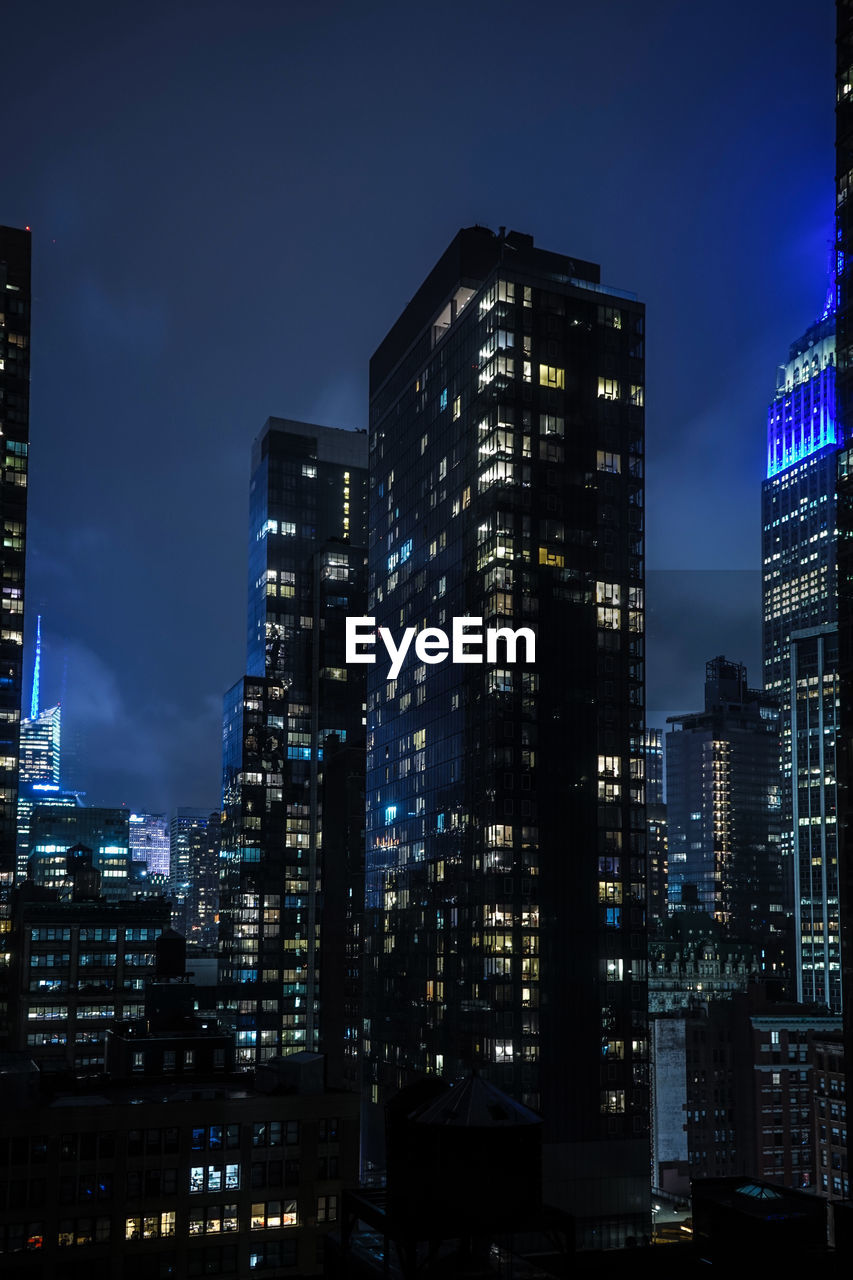 Illuminated buildings in city against sky at night