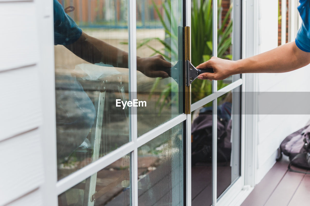 Worker use scraper cleaning window before installing tinting film.