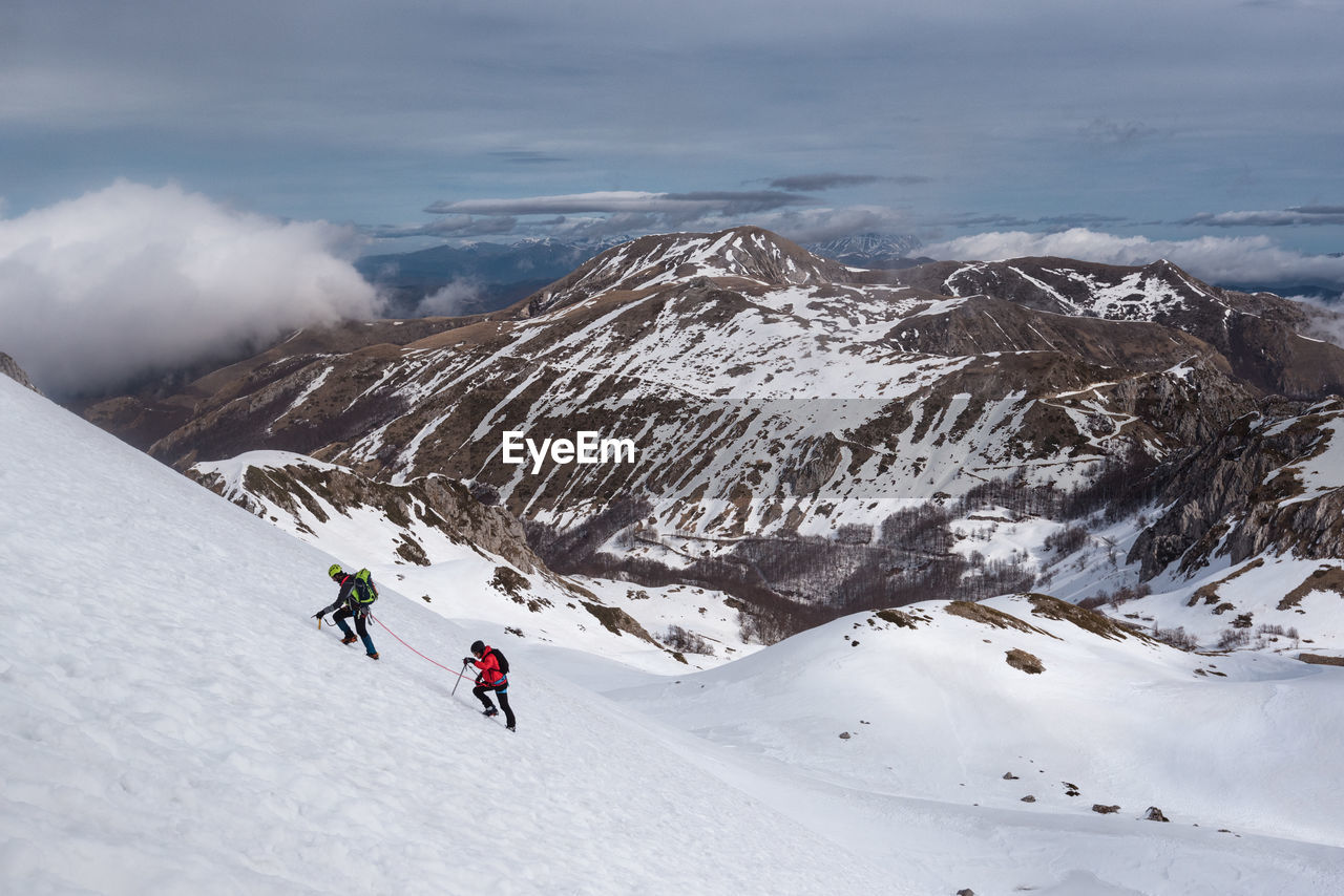 High angle view of people climbing snow covered mountain