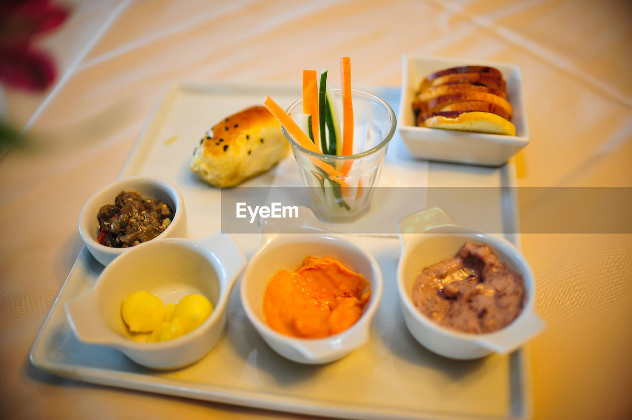 Close-up of dips with bread and shredded vegetables served on plate