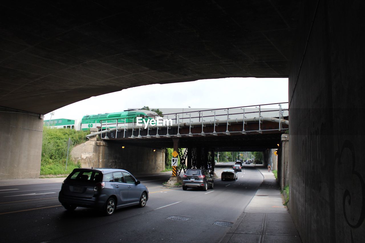 CARS ON ROAD BY BRIDGE AGAINST SKY