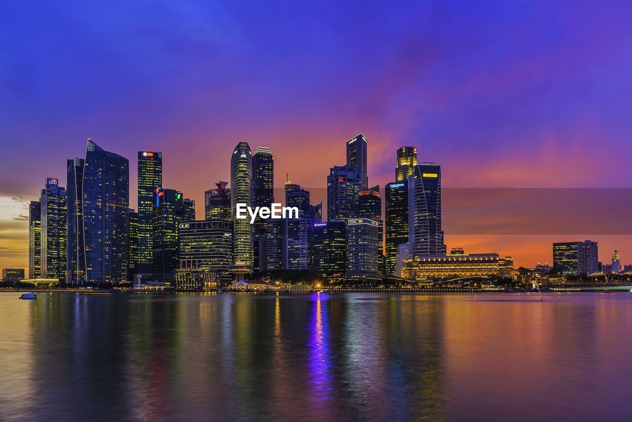 Illuminated cityscape against calm blue sea