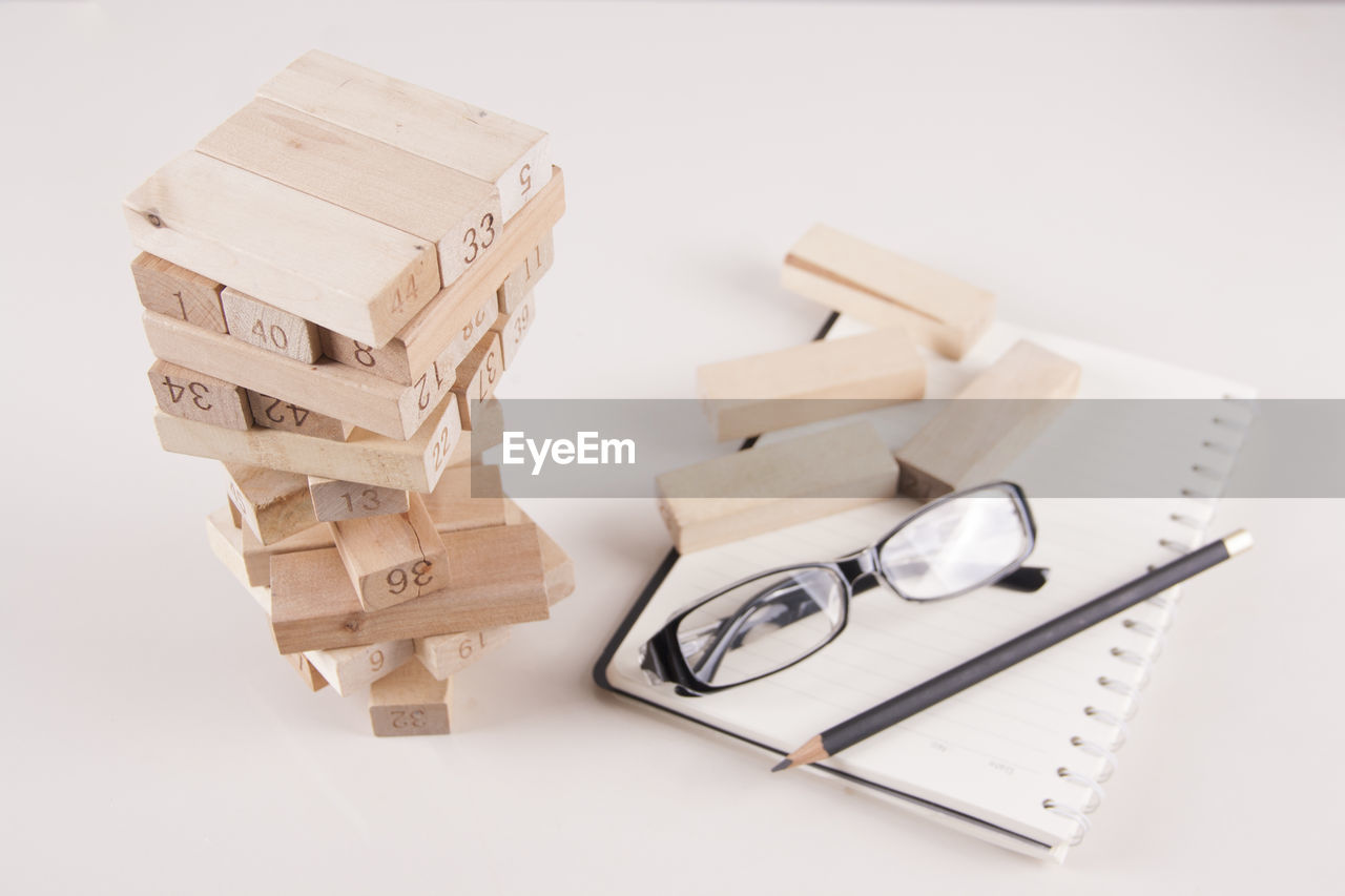 Close-up of stacked wooden blocks and book on white background