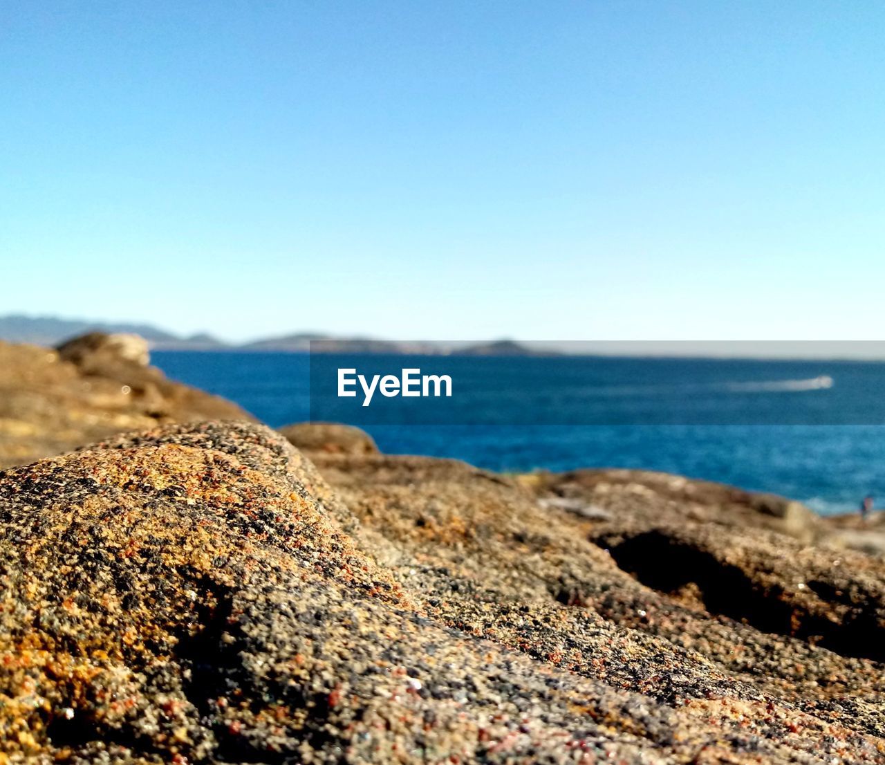 ROCK ON BEACH AGAINST CLEAR SKY