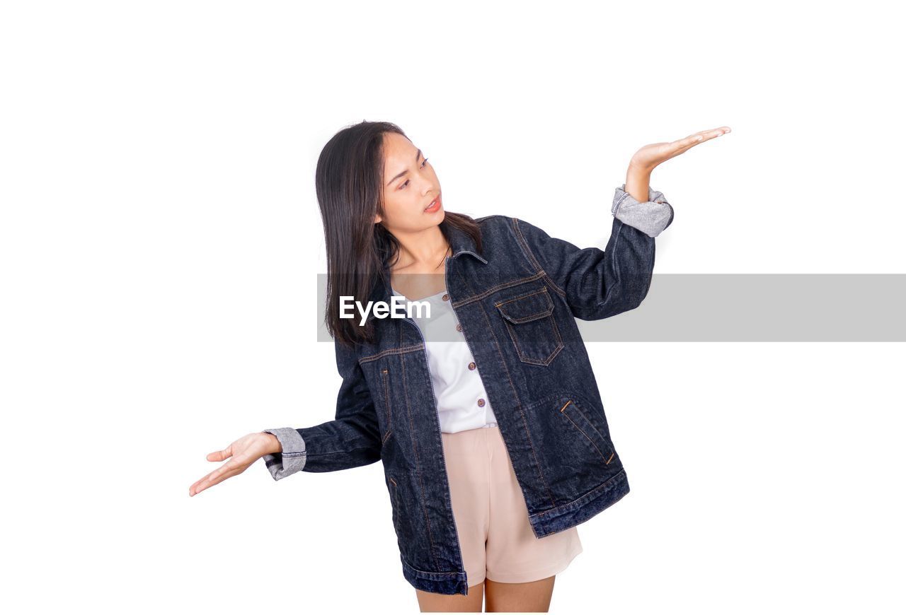 Young woman gesturing while standing against white background