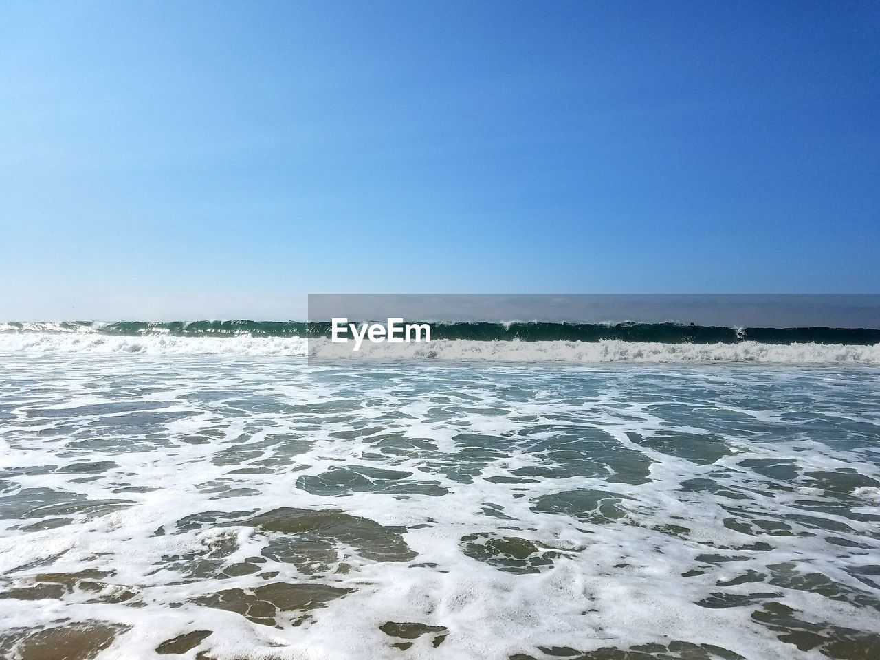 Scenic view of tide against blue sky